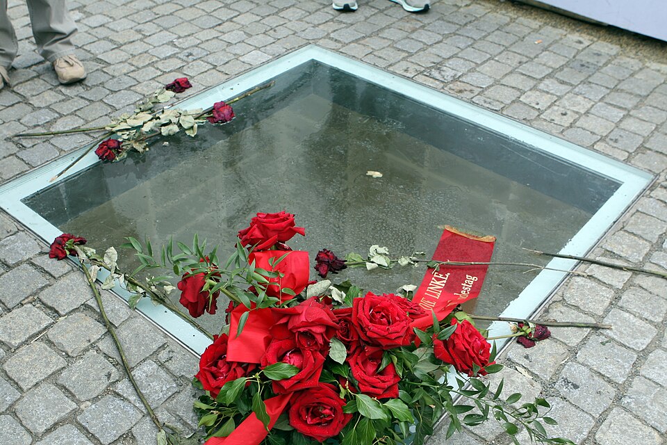 Denkmal zur Erinnerung an die Bücherverbrennung von Micha Ullmann, fotografiert am 13. Mai 2017, mit niedergelegtem Gesteck aus roten Rosen sowie einzelnen Rosen